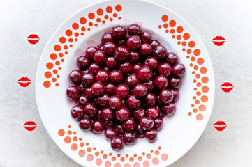 Cherry on a plate with a bright background decorated with lip drawings