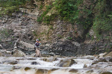 Fototapeta premium Fisherman looks concentrated while fishing in rough river