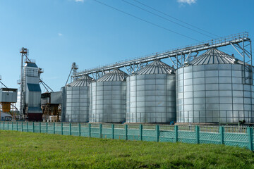 Obraz premium silver silos on agro manufacturing plant for processing drying cleaning and storage of agricultural products, flour, cereals and grain. Large iron barrels of grain. Granary elevator