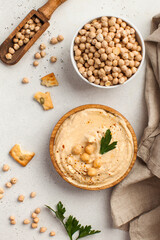 Flatlay Hummus in a wooden plate and raw chickpeas in a bowl. Dishes of chickpeas, a vegetarian dish.