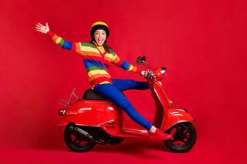 Fototapeta na wymiar Photo portrait of crazy playful girl spreading legs arms riding scooter isolated on vivid red colored background
