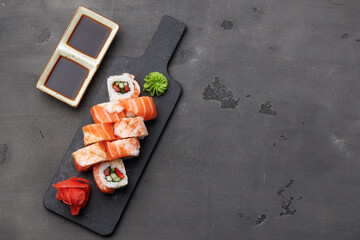 Top view of sushi roll with salmon and prawn on black background