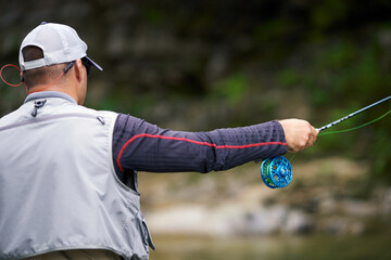 Fisherman in special uniform fishing in mountain river