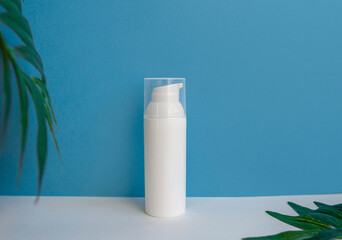 Mockup of cosmetic cream, bottle packaging on a blue background, beauty face and body skin care with tropical leaves. copy space