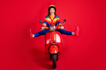 Photo portrait of excited woman spreading legs like star riding scooter isolated on vivid red colored background