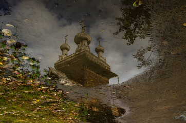 Church of the Ascension of the Lord in the museum of the wooden house "Malye Korely". Reflection in a puddle. Fall. Russia, Arkhangelsk region