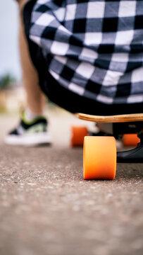 a boy is sitting on the skateboard with the orange weels