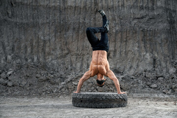 Muscular guy balancing on hands during outdoors training