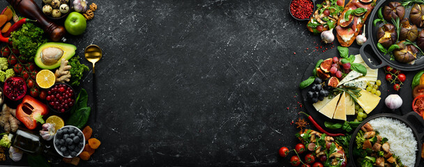 Big set of vegetables, fruits, berries and food on a black stone background. Free space for text....