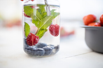 Raspberries, blueberries, and mint drink inside a jar