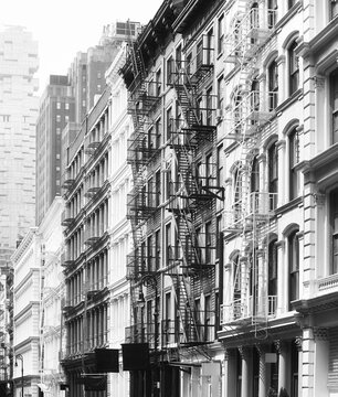 Black and white photo of buildings facades with fire escapes, New York City, USA.