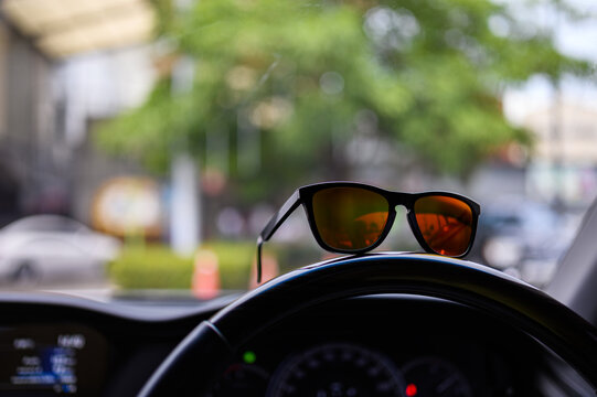 Fashion sunglasses placed on the steering wheel of a car