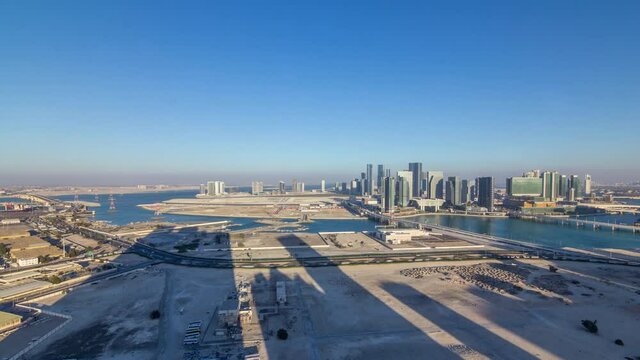 Aerial skyline of Abu Dhabi city centre from above timelapse before sunset with shadows from skyscrapers.