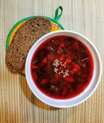  red beetroot soup with potatoes and herbs with toasted rye bread on a light background