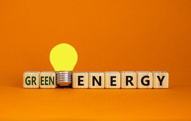 Green energy symbol. Wooden cubes with words 'green energy'. Yellow light bulb. Beautiful orange background. Business, ecological and green energy concept. Copy space.