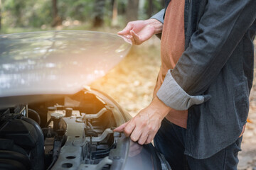 Close up hand man open car hood for repair as maintenance service. Man trying to repair a car engine, looking inside open bonnet