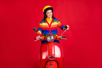Photo portrait of woman fixing regulating mirror on scooter isolated on vivid red colored background