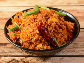 Tasty veg schezwan fried rice served in bowl over a rustic wooden background, Indian cuisine, selective focus