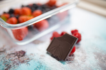 Bitten chocolate bar and raspberries on a colorful placemat