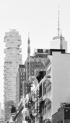 Black and white photo of modern and old buildings with fire escapes, New York City, USA.