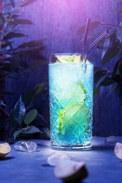 A glass of blue cocktail with lime among the tropics.