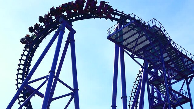 People in multiple cars ride on roller coaster in amusement park sky background