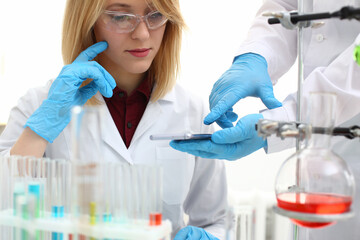 A female doctor in a chemical laboratory holds a smartphone in his hand with display, you can insert a picture or an image you want to write for an advertising company