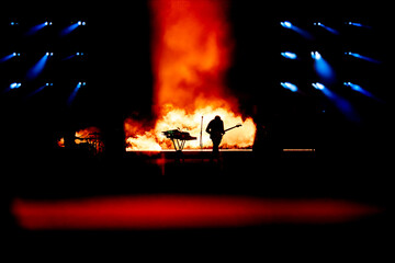 Silhouette of a guitar player in the smoke. The guitarist plays at a rock concert.