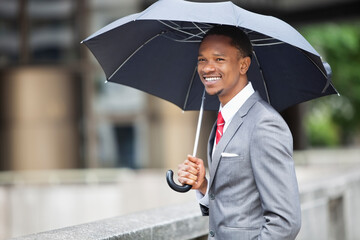 Happy African American businessman holding umbrella