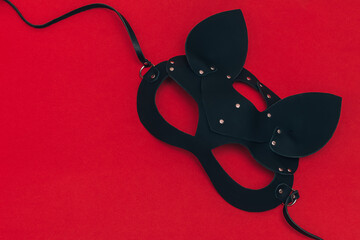 Black leather cat mask on a red background.Concept of Valentine's Day, BDSM communities.Copy space,...