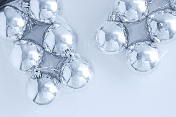Christmas silver balls in two transparent packaging on white background.