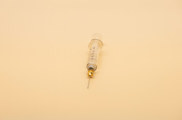 Syringe and needle isolated on beige background.
