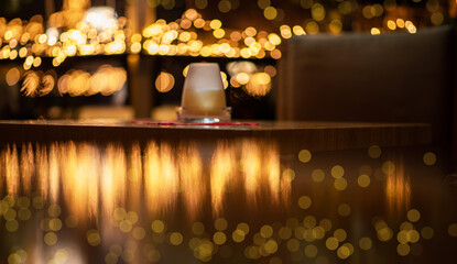 Wood table top with reflect on blur of lighting in night cafe,restaurant background. Selective focus. Christmas lights in the dark. Image of blurred background with warm colorful lights.