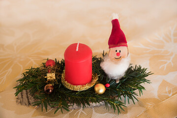 handcrafted advent spray with red candle, santa clause gnome and baubles, golden background
