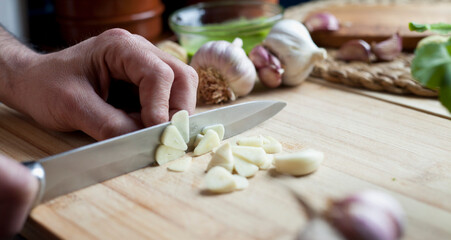 Obraz na płótnie Canvas Chopping garlic activity - male cook is slicing the garlic cloves.