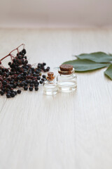 Fototapeta na wymiar elderberry essential oil (tincture, extract, infusion) with fresh elderberry on wooden background