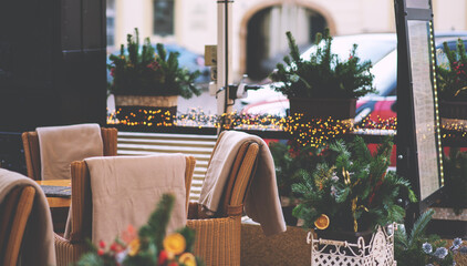 Cozy street cafe in Prague with christmas illumination on the background. Table and armchairs in restaurant with Christmas and new years decorations outdoor.