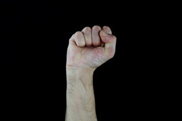 A man raised his fist high. Raised fist gesture for support or solidarity, struggle, opposition, male hand on isolated black background