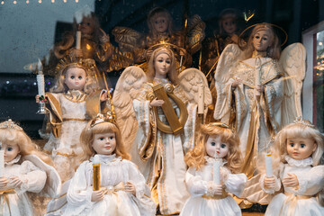 Figures of porcelain dolls of angels with candles in the window at Christmas