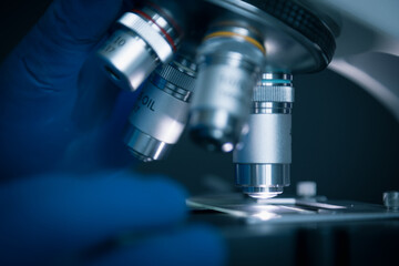 Fototapeta na wymiar Close-up shot of sample slide and microscope with metal lens at laboratory.
