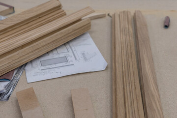 An oak wood bar blocks materials stacked in a wood joiner's workshop with tools and sawdust in the...