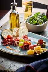 summer picnic with wine and snacks. Flat-lay of charcuterie and cheese board, rose wine, nuts, olives and fruits over wood table background