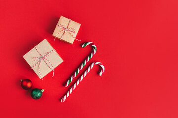 Gift boxes with christmass balls and candy canes on a red background.