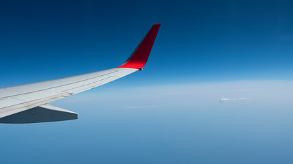 Fototapeta na wymiar A View of Wing of an Airplane from Window Seat Overlooking Clouds and Sky