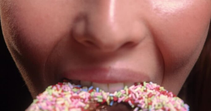 Young woman mouth eating sprinkled donut