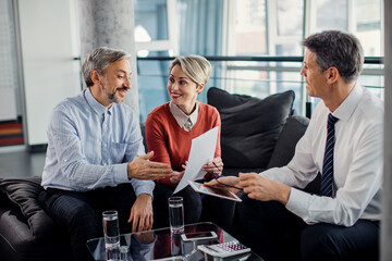 Happy couple talking about paperwork with their financial advisor during the meeting.