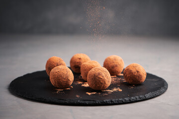 Truffles from dates in carob on a slate Board are sprinkled with carob