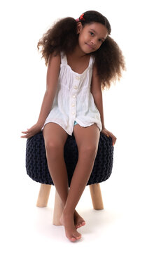 Cute Multiracial Small Girl Sitting On A Stool Seat