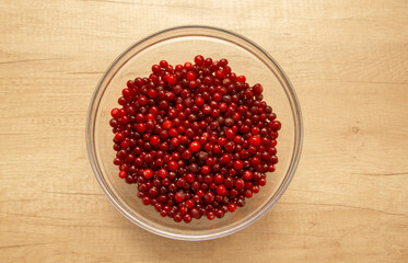 cranberries in a glass bowl on a wooden background, flat lay