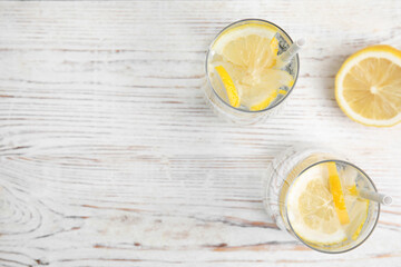 Soda water with lemon slices on white wooden table, flat lay. Space for text
